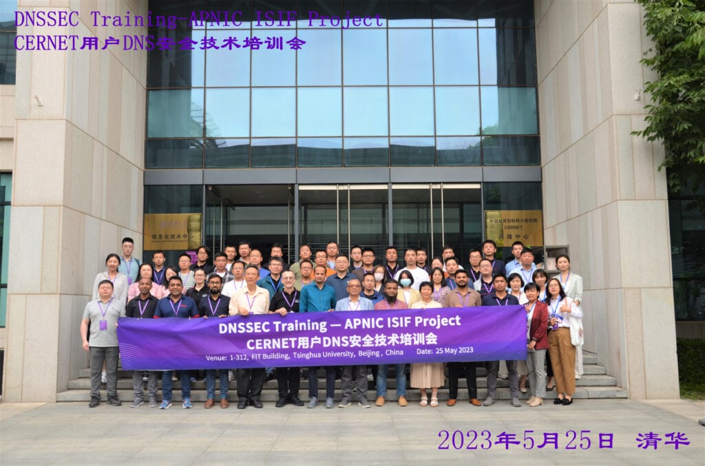 Staff from Tsingua university stand outside a university building holding a banner with information about a DNSSEC training session that took place on 25 May, 2023.