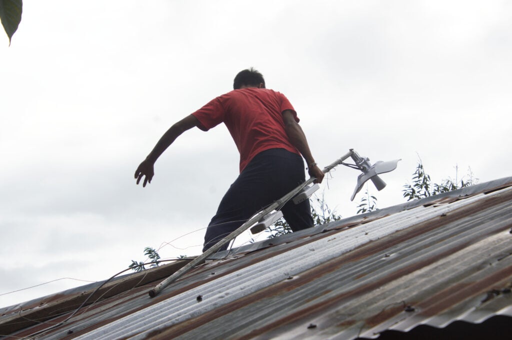 A worker carries P2P equipment across a rooftop.