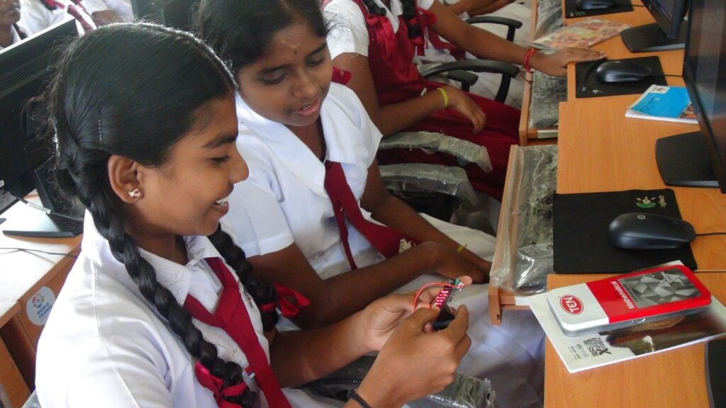 Image shows two girls in school uniforms working together.
